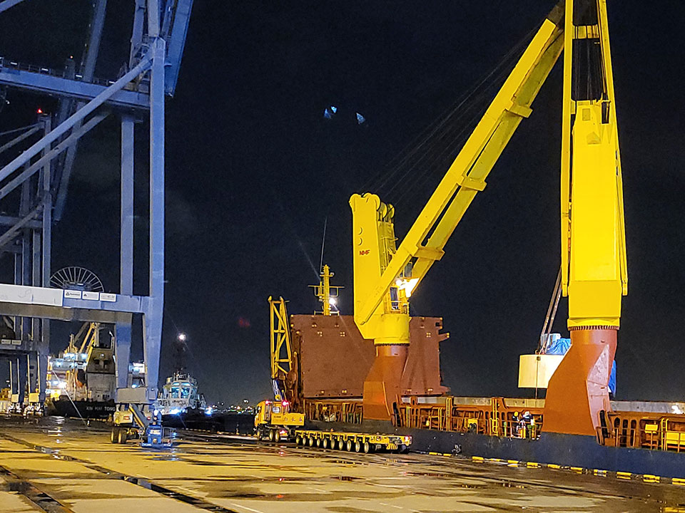 Photo depicting a large yellow crane on a shipyard next to a Peck Tiong Choon yellow carrier truck.